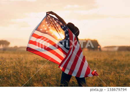 Woman farmer in the agricultural field with american flag on sunset. 138679794