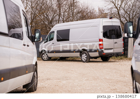 White commercial cargo van parked on a gravel lot near leafless autumn trees in soft daylight. 138680417