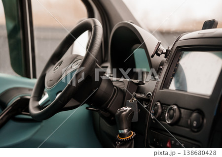 Close up view of a dark dashboard and steering wheel inside a commercial transport vehicle interior Close up view of a dark dashboard and steering wheel inside a commercial transport vehicle interior 138680428