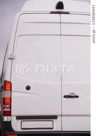Rear view of a white commercial delivery van parked outdoors in bright daylight. 138680441