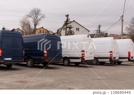 Row of blue and white commercial delivery vans parked in an outdoor lot near residential buildings. Row of blue and white commercial delivery vans parked in an outdoor lot near residential buildings. 138680449