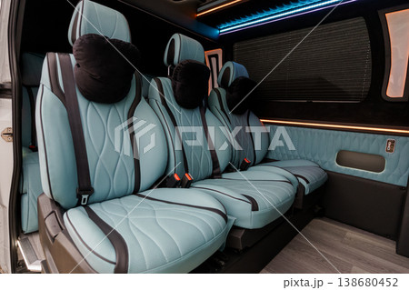 Interior of a luxury passenger van featuring light blue quilted leather seats and ambient blue LED lighting. Interior of a luxury passenger van featuring light blue quilted leather seats and ambient blue LED lighting. 138680452