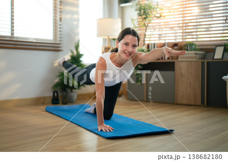Female performing core stability balance exercise on yoga mat indoors, Practicing Bird Dog Exercise 138682180
