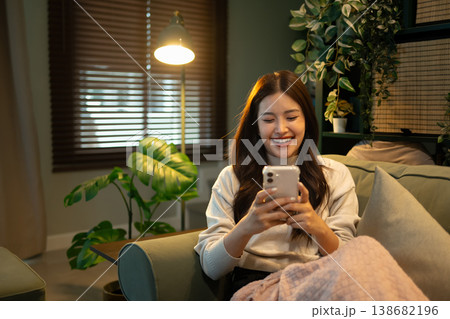 Young woman browsing on smartphone while sitting comfortably on sofa at home Young woman browsing on smartphone while sitting comfortably on sofa at home 138682196