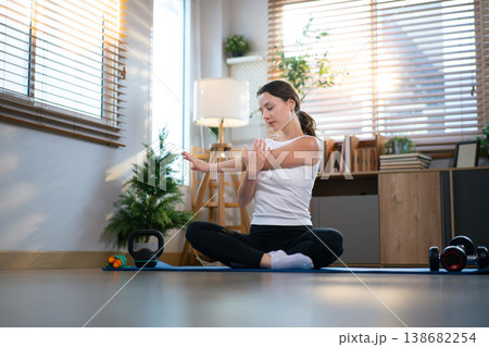 Young woman practicing stretching exercise on yoga mat indoors. Young woman practicing stretching exercise on yoga mat indoors. 138682254