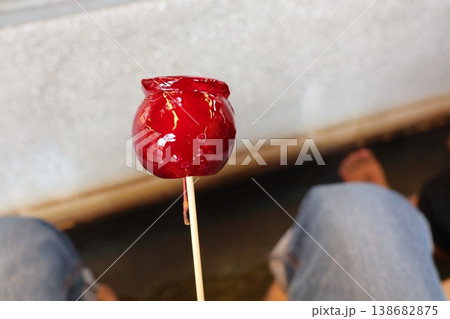 手に持ったりんご飴の鮮やかなスイーツ写真 138682875