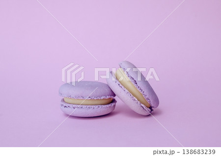 Pair of lavender French macarons on solid lilac background, purple monochrome dessert photography for cafe menu Pair of lavender French macarons on solid lilac background, purple monochrome dessert photography for cafe menu 138683239