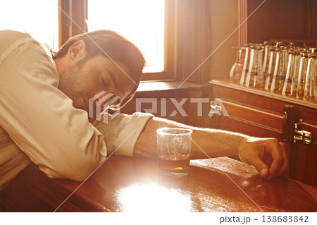 Sleeping, counter and man with whiskey, alcoholic and unhealthy habit with depression, tired and overworked. Person, addict and guy with a drink, exhausted and drunk with handover, brandy and booze 138683842