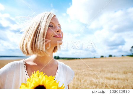 Freedom, relax and calm woman with a sunflower on a wheat field for travel or vacation. Peace, face and female person in nature with a flower in nature for holiday, journey or adventure outdoor 138683959