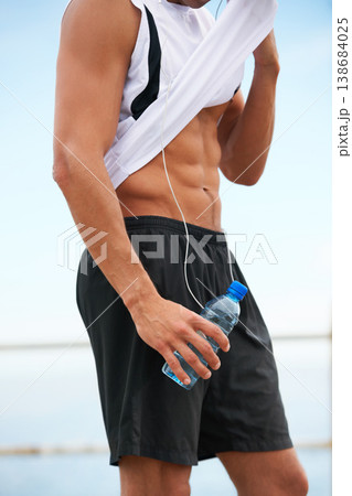 Person, abs and fitness, water and wipe sweat with bottle and wellness, runner outdoor for cardio and break after workout. Hydration, h2o and training with health, stomach muscle and sports athlete 138684025