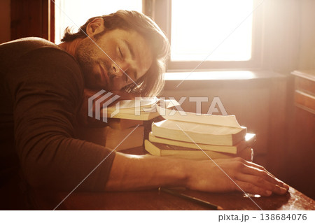 Sleeping, tired and man with books, student and fatigue with education, university and burnout. Person, academic and guy with literature, novel and exhausted with lens flare, insomnia and dreaming 138684076