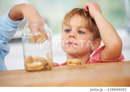 Cute, cookies jar and boy kid by the kitchen counter eating a sweet snack or treat at home. Smile, dessert and hungry young child enjoying biscuits by a wooden table in a modern family house. Cute, cookies jar and boy kid by the kitchen counter eating a sweet snack or treat at home. Smile, dessert and hungry young child enjoying biscuits by a wooden table in a modern family house. 138684083