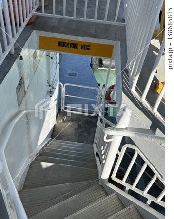 Staircase leading down from ferry deck, featuring caution sign and white railings Staircase leading down from ferry deck, featuring caution sign and white railings 138685815