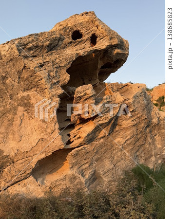 Rock formation at sunset with eroded textures and natural patterns against clear blue sky Rock formation at sunset with eroded textures and natural patterns against clear blue sky 138685823