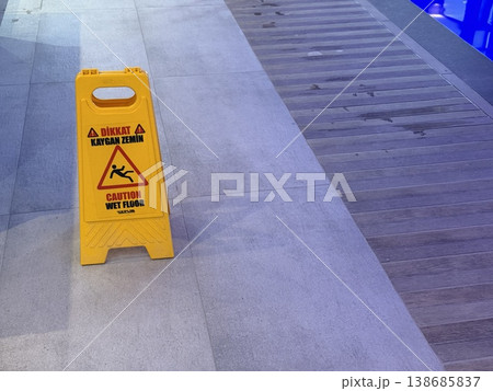 Caution wet floor sign on tiled surface near swimming pool, safety warning, indoor setting background Caution wet floor sign on tiled surface near swimming pool, safety warning, indoor setting background 138685837