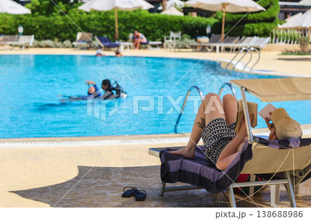 Egypt, Sharm el-Sheikh - October 1, 2025. A tourist on a sun lounger reads a book against the backdrop of the Savoy Hotel swimming pool. Editorial Egypt, Sharm el-Sheikh - October 1, 2025. A tourist on a sun lounger reads a book against the backdrop of the Savoy Hotel swimming pool. Editorial 138688986