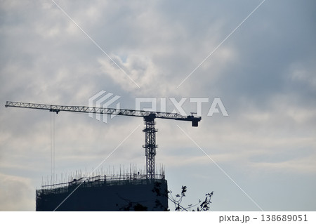 Close-up of construction crane with clear sky in background. Construction scene and city development. Close-up of construction crane with clear sky in background. Construction scene and city development. 138689051