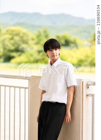 屋外のテラスで寄りかかる男子高校生 138690534