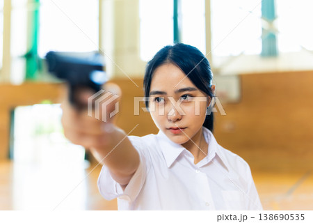 銃を構えて横を見る女子高生 138690535