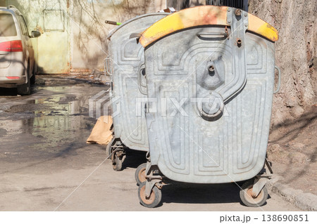 Metal trash cans. Dumpsters being full with garbage. Garbage, waste lots and junk dump. Sunny day. 138690851