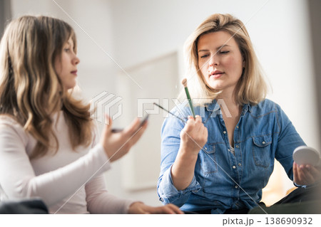 Woman holding makeup brushes looking at cosmetic products 138690932