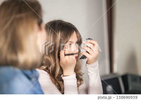 Young woman applying eye makeup, holding compact mirror Young woman applying eye makeup, holding compact mirror 138690939