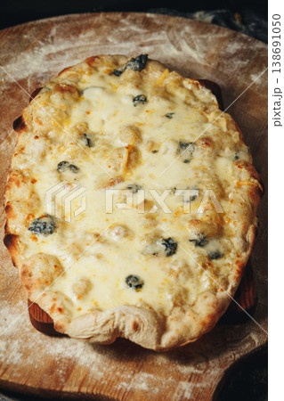 Traditional Italian pinsa quattro formaggi with melted mozzarella gorgonzola parmesan and emmental cheese on a wooden board with flour. 138691050