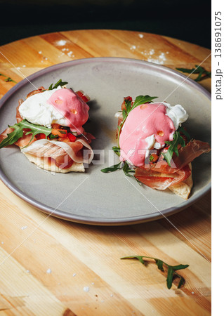 Gourmet poached eggs on prosciutto and flatbread with vibrant pink beet hollandaise sauce and fresh arugula. 138691075