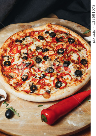 Traditional Italian pinsa romana capricciosa topped with tomato sauce mozzarella ham black olives artichokes and mushrooms on a wooden board. Traditional Italian pinsa romana capricciosa topped with tomato sauce mozzarella ham black olives artichokes and mushrooms on a wooden board. 138691078