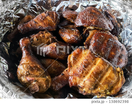 Close-up of freshly smoked chicken drumsticks and thighs served in aluminum foil after barbecue cooking Close-up of freshly smoked chicken drumsticks and thighs served in aluminum foil after barbecue cooking 138692398