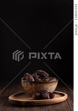 Medjoul Dates in Rustic Ceramic Bowl on Dark Wooden Background 138693105
