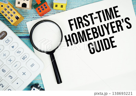 Notepad with "First-Time Homebuyer's Guide" with Calculator, magnifying glass and house model on wooden background 138693221