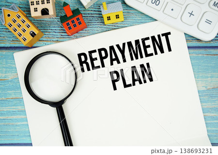 Notepad with "Repayment Plan" with Calculator, magnifying glass and house model on wooden background Notepad with "Repayment Plan" with Calculator, magnifying glass and house model on wooden background 138693231