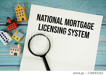 Notepad with "NMLS National Mortgage Licensing System" with magnifying glass and house model on wooden background 138693262
