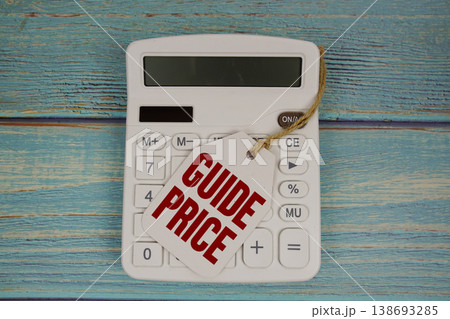 Price tag with "GUIDE PRICE" on calculator on a rustic blue wooden surface 138693285