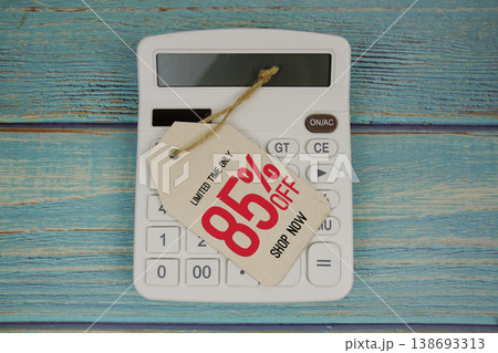 Sale 85% off Shop Now with price tag and calculator on wooden background Sale 85% off Shop Now with price tag and calculator on wooden background 138693313