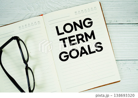 Notepad with message "Long Term Goals" and eyeglass on wooden background Notepad with message "Long Term Goals" and eyeglass on wooden background 138693320