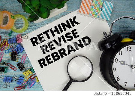 Rethink Revise Rebrand text on a paper surrounded by office supplies, a magnifying glass, and a clock on a blue wooden surface Rethink Revise Rebrand text on a paper surrounded by office supplies, a magnifying glass, and a clock on a blue wooden surface 138693343