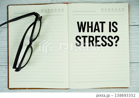Notepad with message "What Is Stress?" and eyeglass on wooden background 138693352