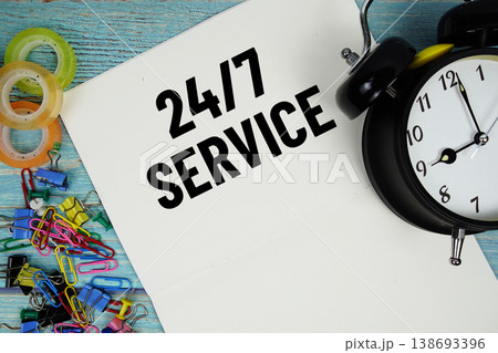 247 Service text with alarm clock and colorful office supplies on a blue wooden surface 138693396
