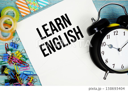 Learn English text with alarm clock and colorful office supplies on a blue wooden surface Learn English text with alarm clock and colorful office supplies on a blue wooden surface 138693404