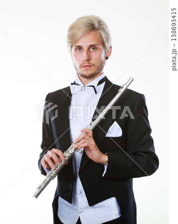 Male flutist wearing tailcoat holds flute 138693415