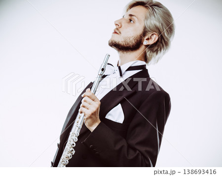 Male flutist wearing tailcoat holds flute 138693416