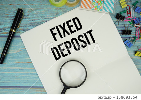 Fixed Deposit text written on notepad with magnifying glass flat lay on wooden background Fixed Deposit text written on notepad with magnifying glass flat lay on wooden background 138693554
