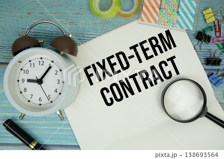 Fixed-Term Contract text written on notepad with alarm clock and magnifying glass flat lay on wooden background 138693564