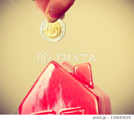 Person putting money into house piggybank Person putting money into house piggybank 138693629