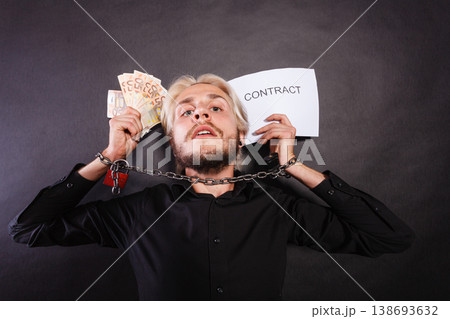 Man with chained hands holding contract and money Man with chained hands holding contract and money 138693632