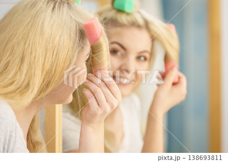Blonde woman using hair rollers Blonde woman using hair rollers 138693811