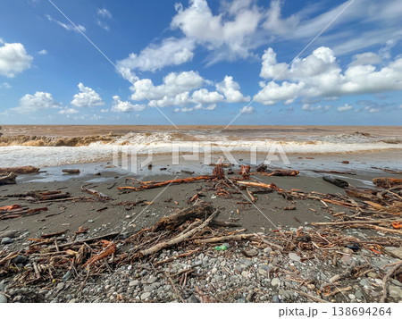 A littered pebble beach with rough waves and accumulations of debris and plastic. A littered pebble beach with rough waves and accumulations of debris and plastic. 138694264