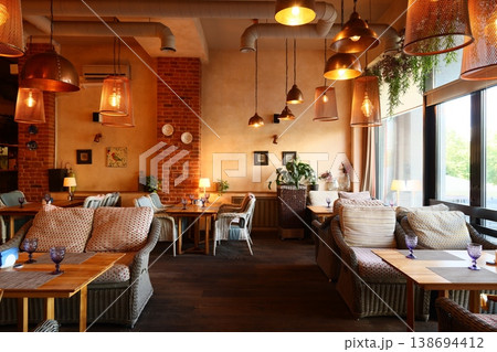Industrial styled cafe featuring inviting seating and warm accents 138694412